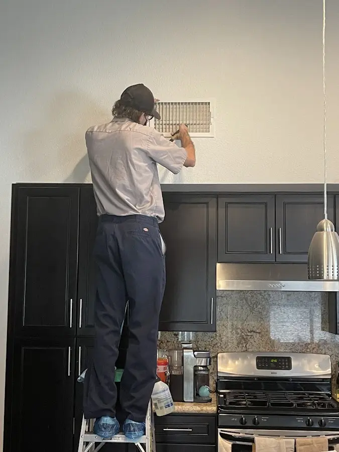 Technician inspecting an air vent during HVAC service in Los Angeles